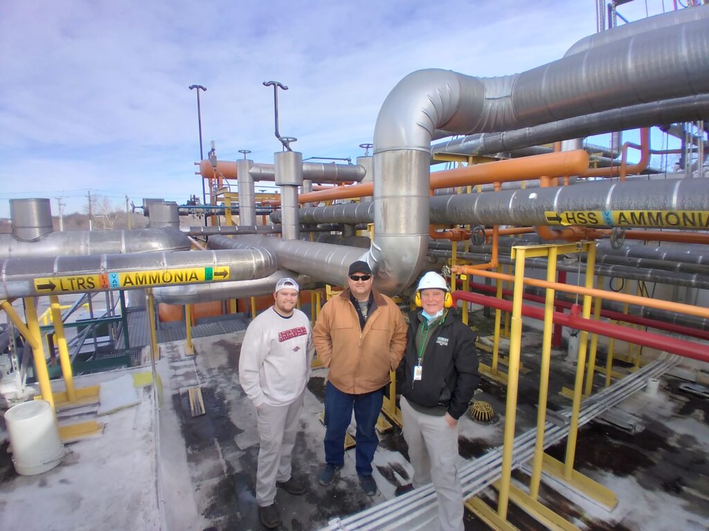 Three men standing in front of a large pipe.
