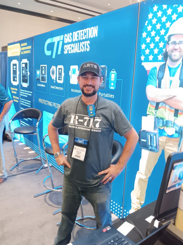 A man standing in front of a wall with a large poster behind him.