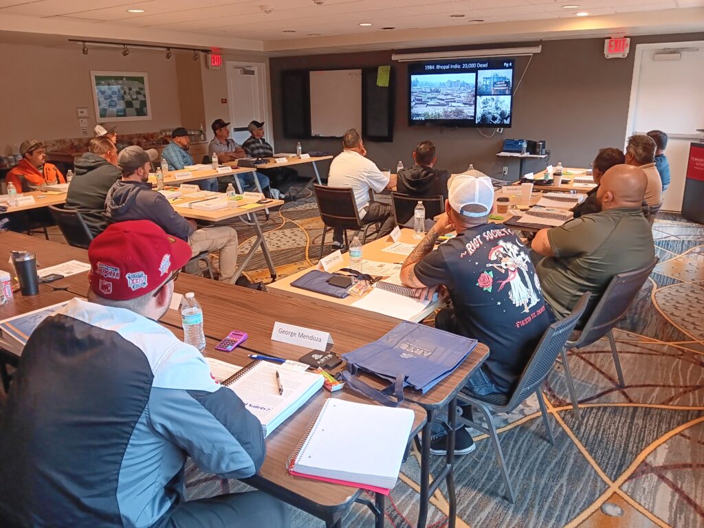 A group of people sitting at tables in front of a tv.