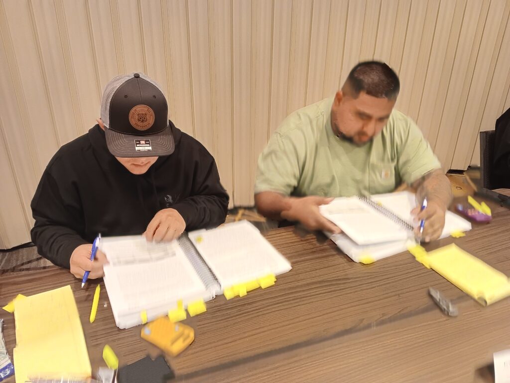 Two men sitting at a table with papers on them.