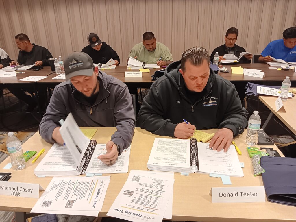 Two men sitting at a table with papers on them.