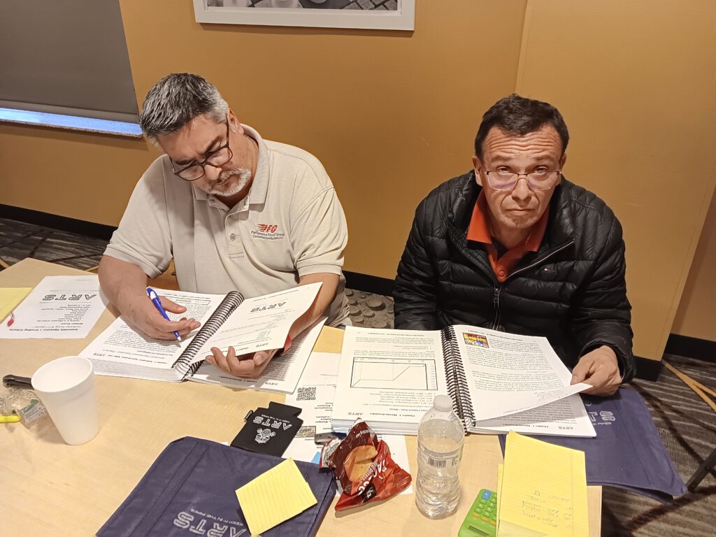 Two men sitting at a table with papers and pens.