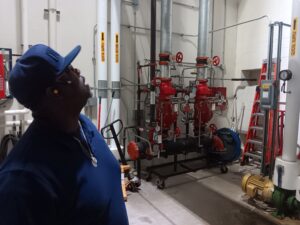 A man in blue shirt looking at pipes.