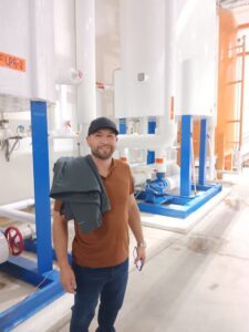 A man holding two wrenches in front of some pipes.