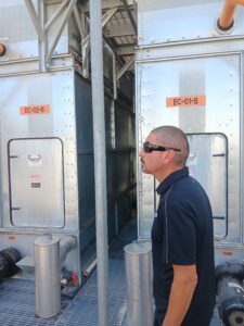 A man standing in front of two large metal trailers.