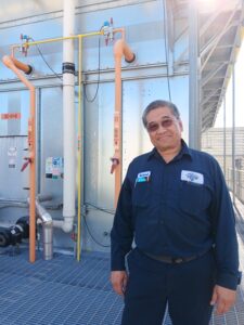A man standing in front of pipes and tanks.