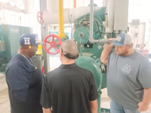 Three men standing in front of a machine.