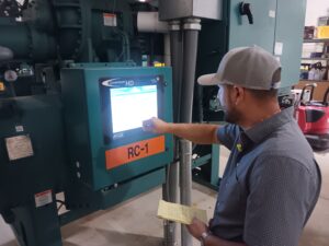 A man is touching the screen of an electrical panel.