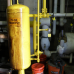 A yellow pipe with pipes and valves in the background.