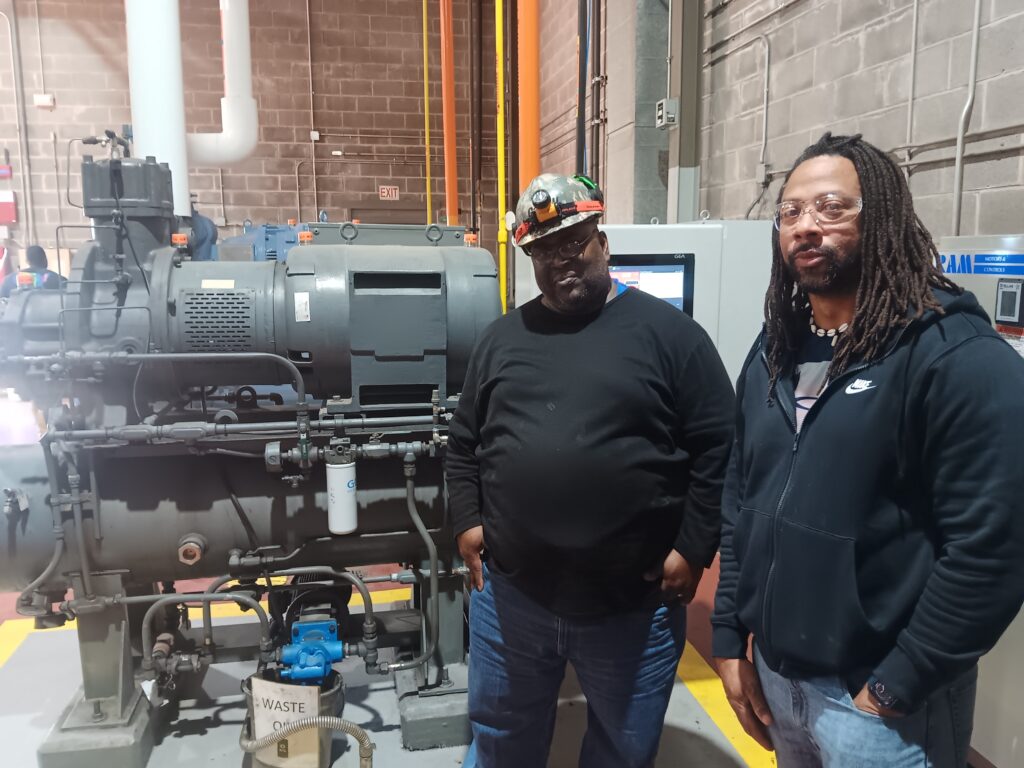 Two men standing next to a large machine.