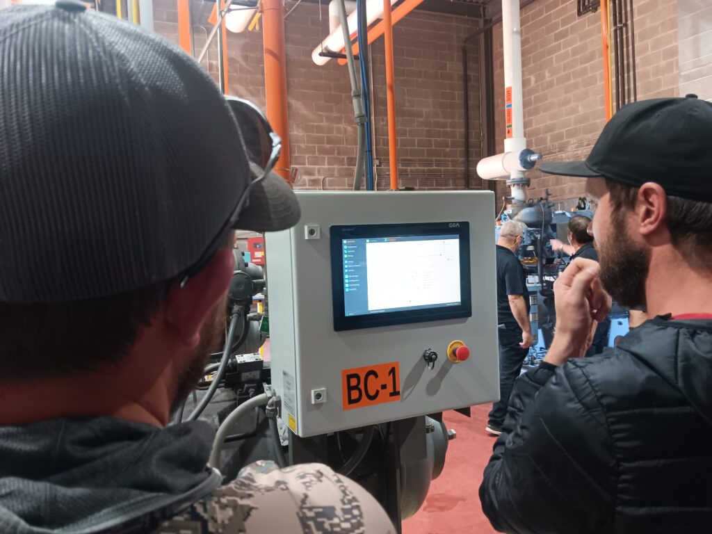 A man is looking at the screen of a video camera.