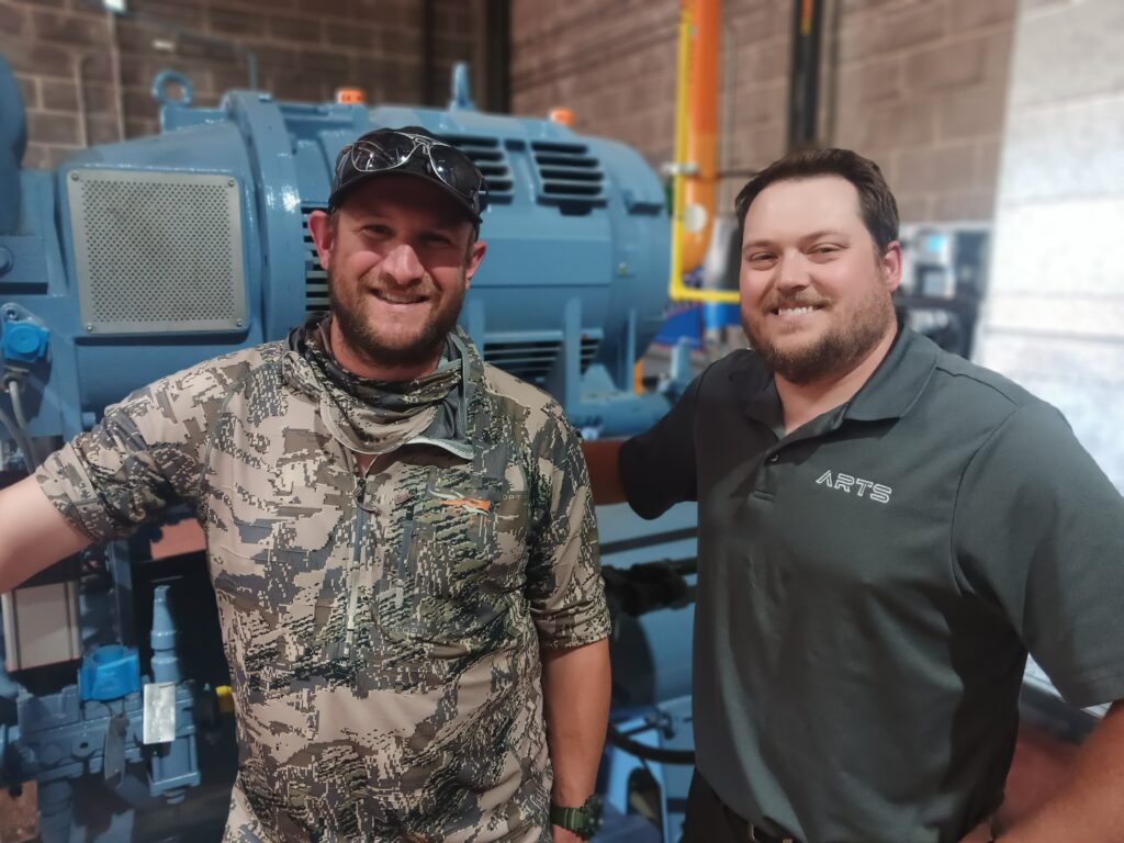 Two men standing next to each other in front of a machine.