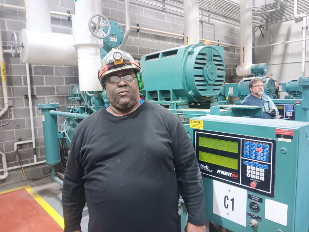 A man in a hard hat standing next to an industrial machine.