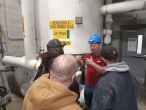 A group of people standing around in front of some pipes.