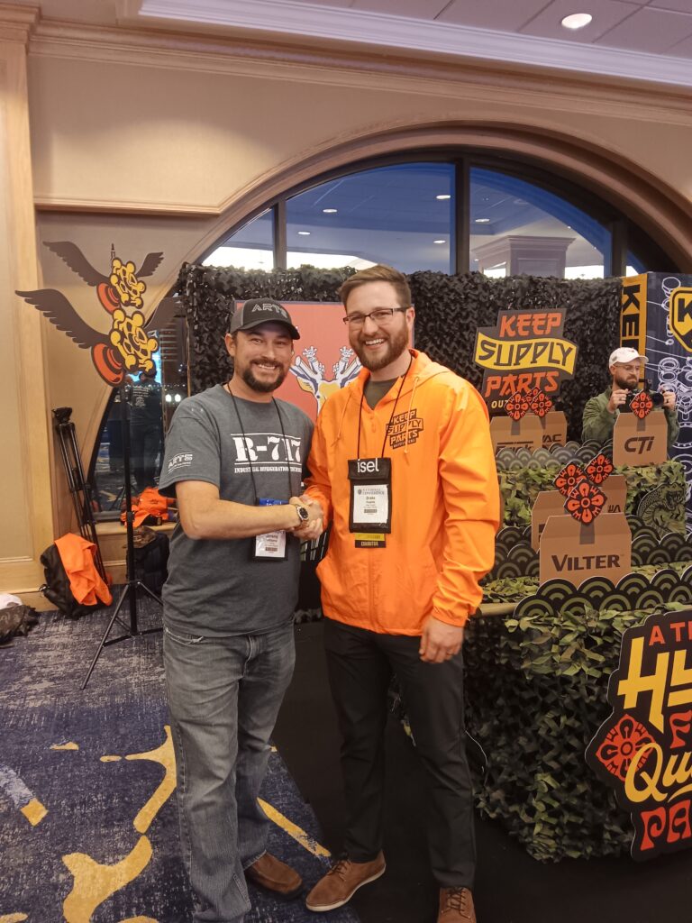 Two men standing next to each other in front of a wall.