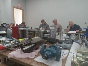 A group of men sitting around a table with various machines.