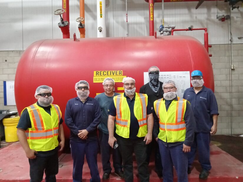 A group of men standing next to a red tank.