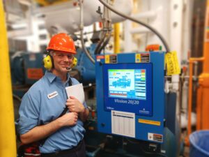 A man in an orange hard hat standing next to a machine.