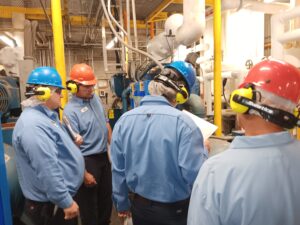 A group of people wearing hard hats and ear muffs.