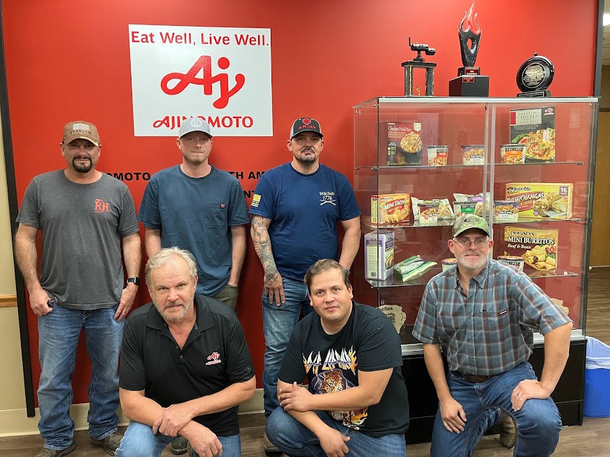 A group of men standing in front of a sign.